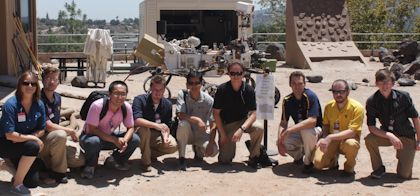 The team poses in front of robots at the NASA Jet Propulsion Laboratory